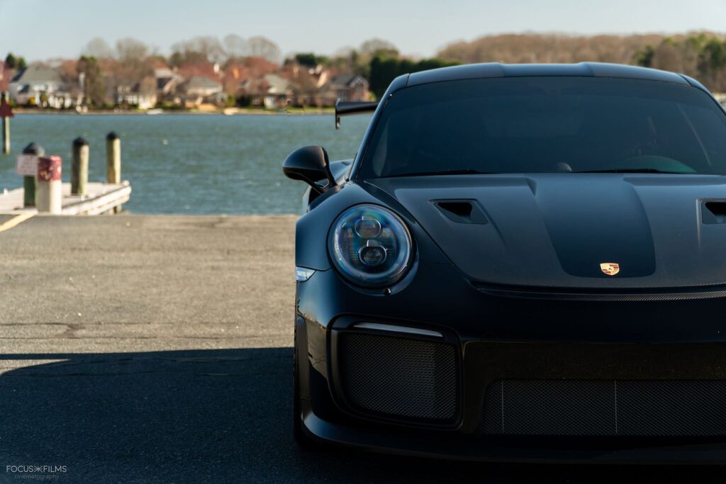 A tinted porsche sits parked at a harbor.