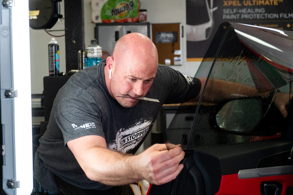 Mike Burke smoothes out car window tint film.